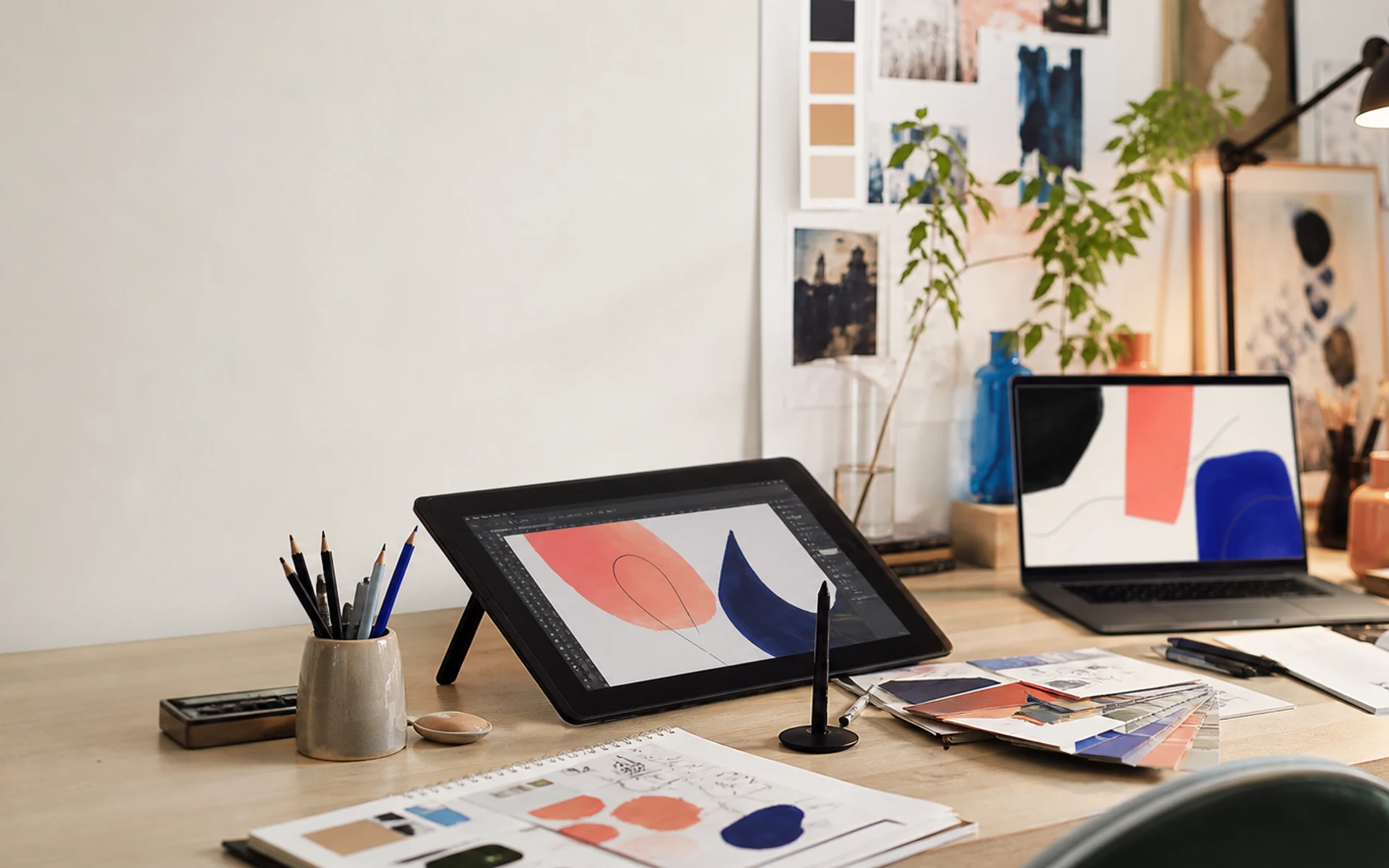 Moderner digitaler Kunstarbeitsplatz mit Tablet, Skizzenbuch und Farbmustern